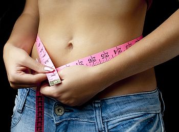 woman measuring her slim waist
